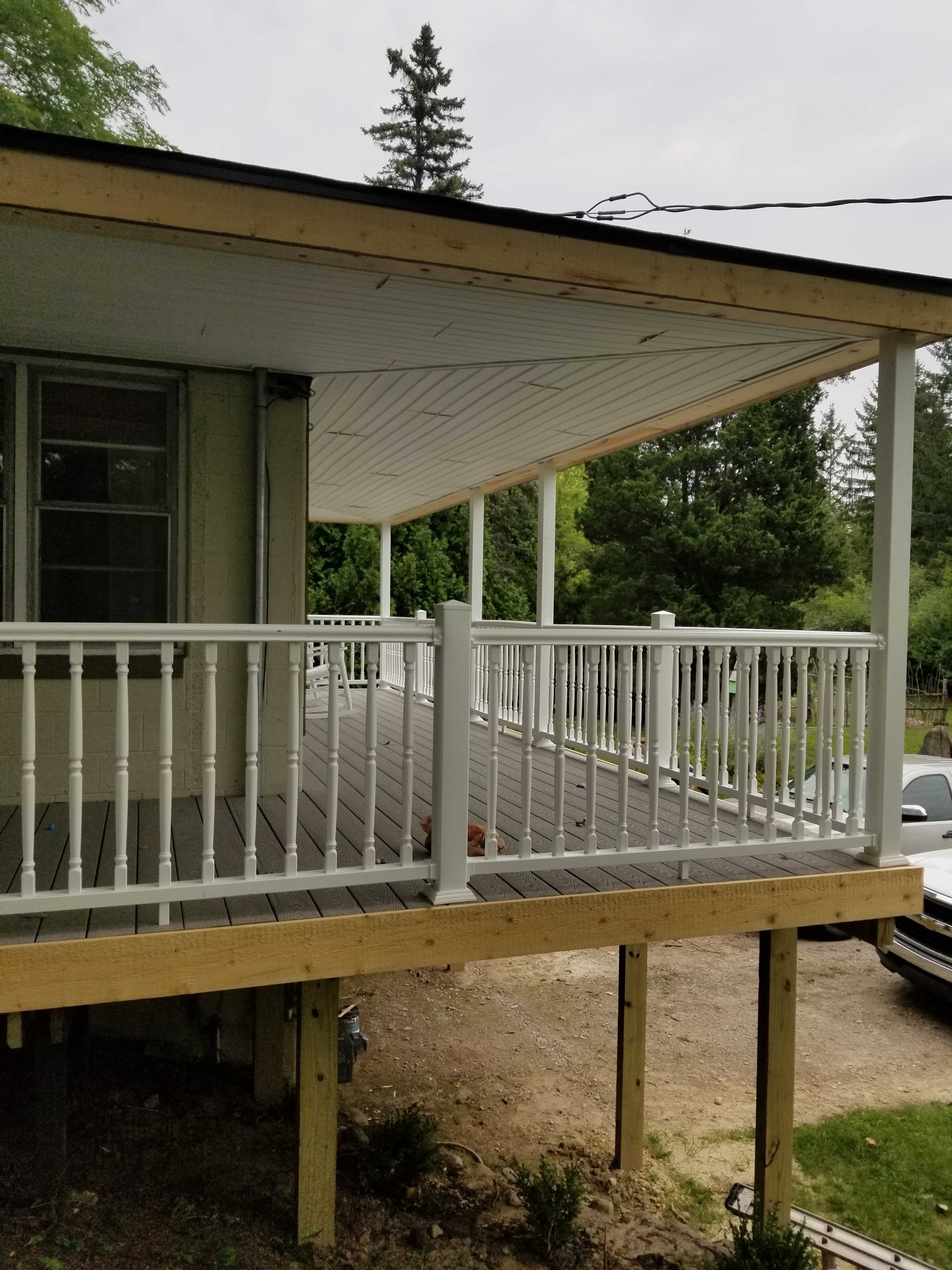 A custom raised deck on the second story of a hillside house with roofing and awning.